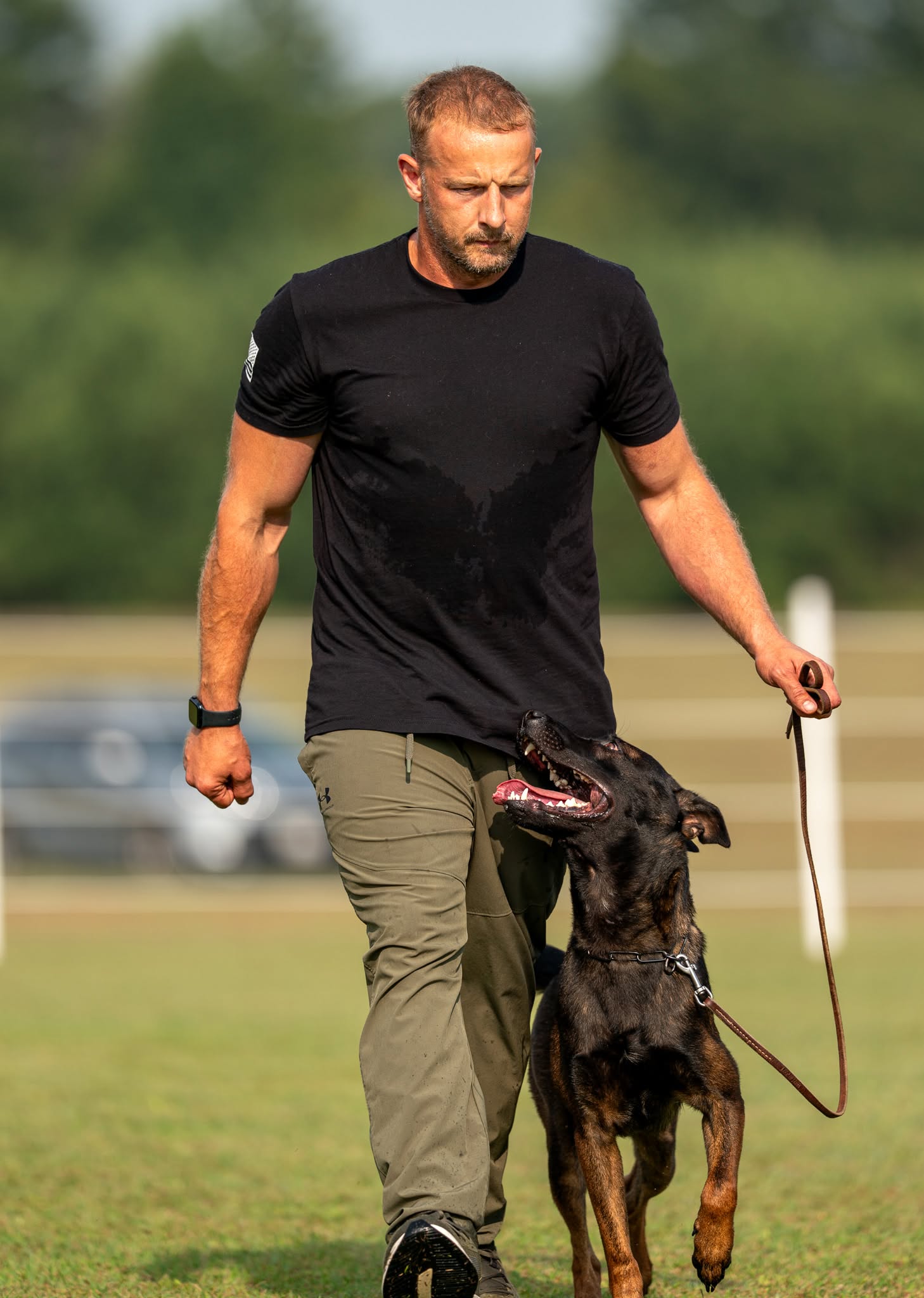 Trainer practicing a focused competition heel with a dog outdoors