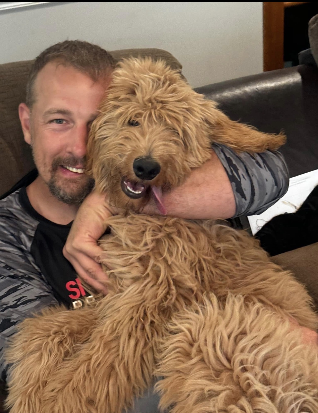 Trainer hugging a happy Goldendoodle indoors during overnight boarding